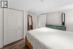 Bedroom with dark wood-style floors, recessed lighting, and a closet -