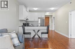 Kitchen with a peninsula, freestanding refrigerator, tasteful backsplash, white cabinets, and dark wood-style flooring -