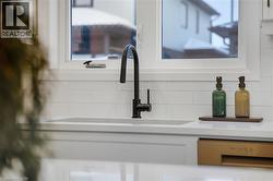 Kitchen view of backsplash, stainless steel dishwasher, white cabinetry, and light stone countertops -