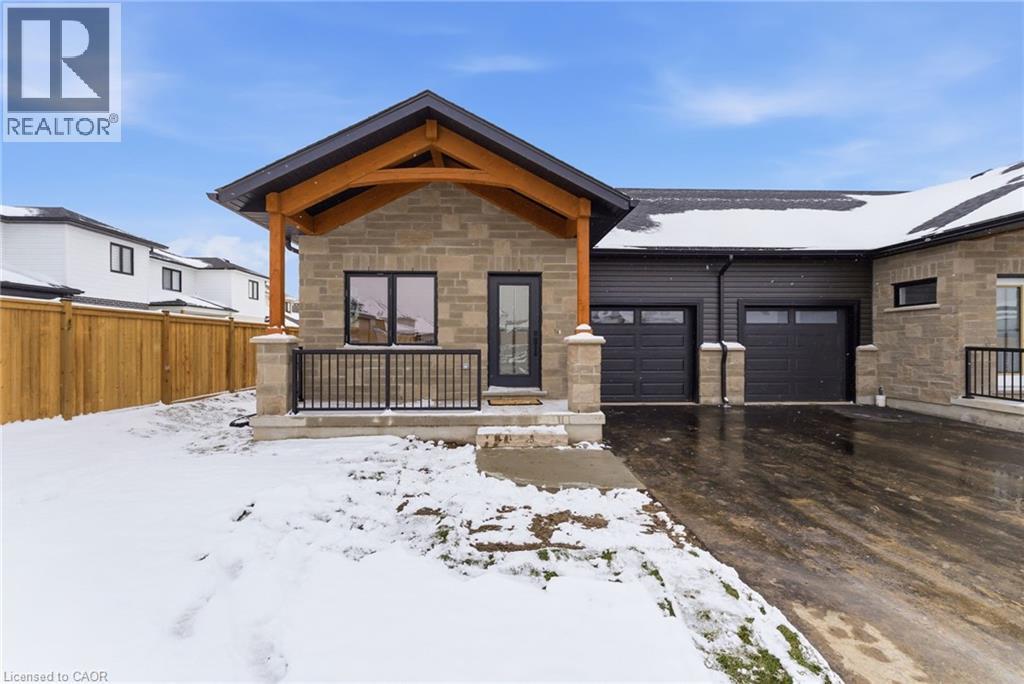View of front of house featuring stone siding, a porch, driveway, and an attached garage - 29 Weymouth Street Unit# 17, Elmira, ON - Outdoor