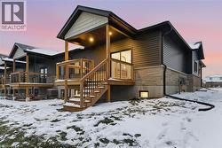 Back of house with a wooden deck, stone siding, and stairway -