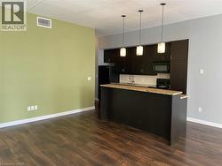 Kitchen featuring pendant lighting, black appliances, dark wood-style floors, light stone countertops, and backsplash -