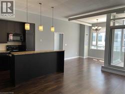 Kitchen with black appliances, pendant lighting, dark wood finished floors, a chandelier, and a kitchen island -