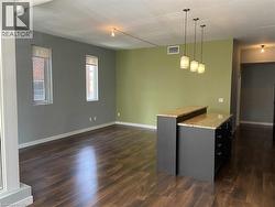 Kitchen featuring pendant lighting, open floor plan, dark wood-type flooring, and light stone counters -
