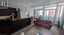 Kitchen featuring a chandelier, dark wood-type flooring, decorative light fixtures, black microwave, and dark brown cabinetry -