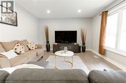 Living area with light wood finished floors and recessed lighting -
