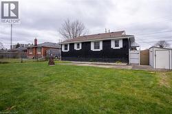 Back of property featuring a storage unit, brick siding, and a gate -