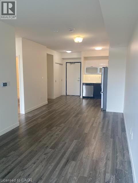 Unfurnished living room with dark wood-style floors and baseboards - 128 King Street Unit# 507, Waterloo, ON - Indoor Photo Showing Other Room