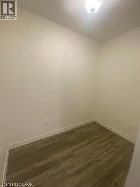 Empty room with dark wood finished floors and baseboards - 128 King Street Unit# 507, Waterloo, ON - Indoor Photo Showing Other Room
