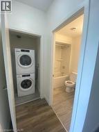 Laundry room featuring dark wood-style flooring and stacked washer / drying machine -