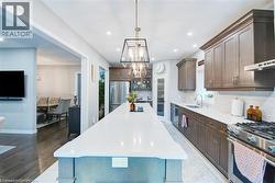 Kitchen featuring high end appliances, tasteful backsplash, a kitchen island, premium range hood, and glass insert cabinets -