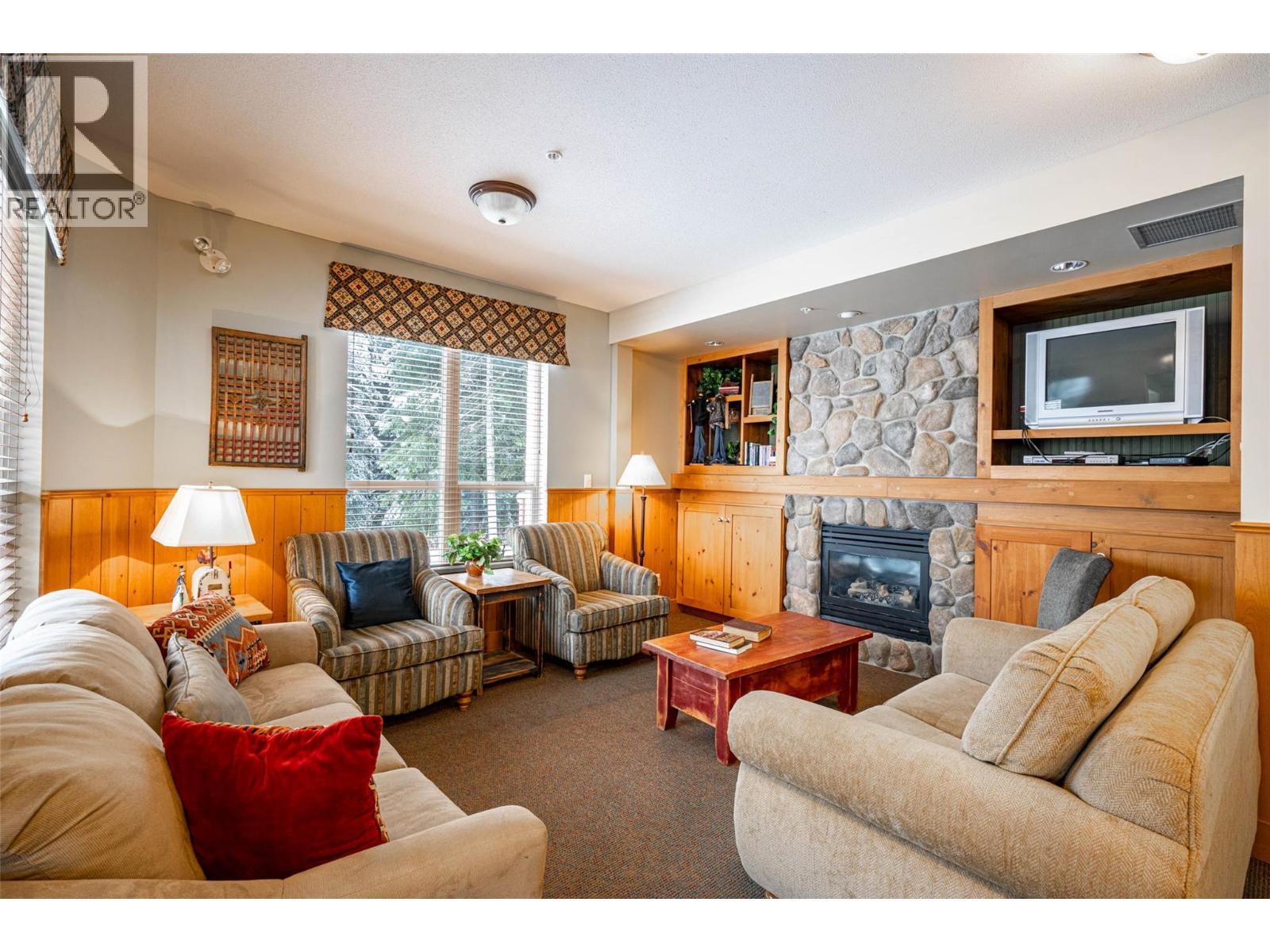 Communal area in the Wildwood Building - 9812 Silver Star Road Unit# 103, Vernon, BC - Indoor Photo Showing Living Room With Fireplace