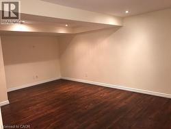 Finished basement with dark wood-type flooring and recessed lighting -