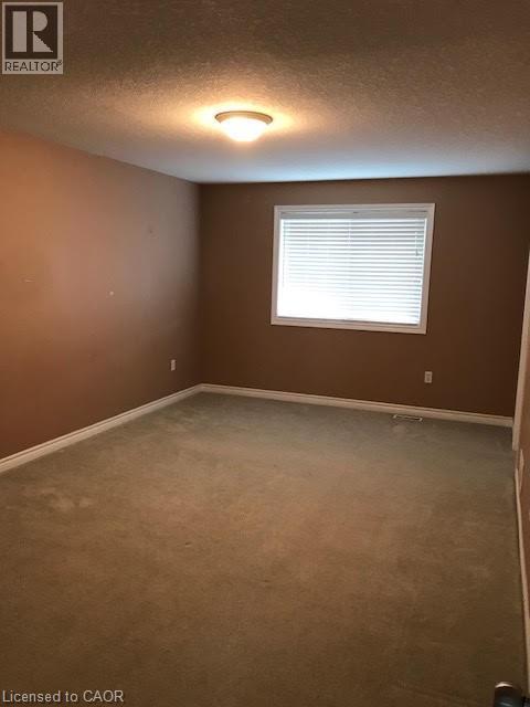 Carpeted spare room featuring a textured ceiling and baseboards - 567 Chablis Drive, Waterloo, ON - Indoor Photo Showing Other Room