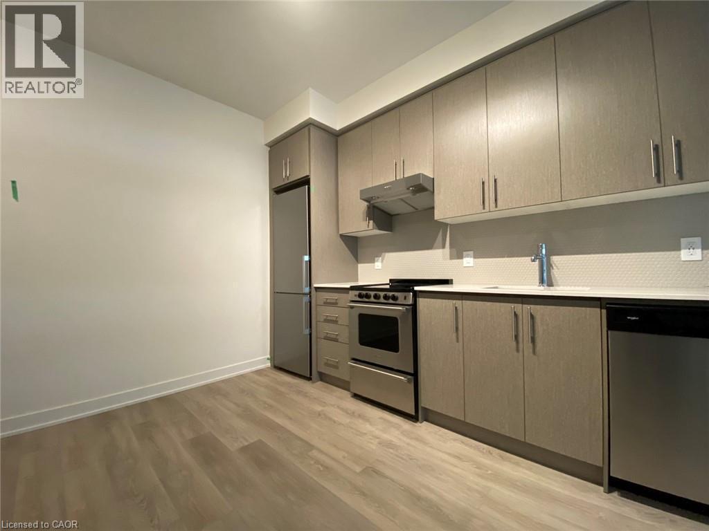 Kitchen with appliances with stainless steel finishes, light countertops, under cabinet range hood, light wood-style floors, and gray cabinetry - 212 King William Street Unit# 1010, Hamilton, ON - Indoor Photo Showing Kitchen