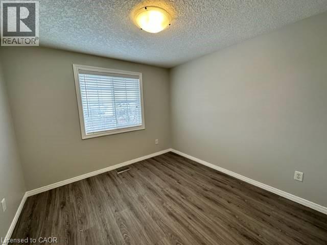 Unfurnished room with a textured ceiling and dark wood-style flooring - 750 Paris Boulevard Unit# 1, Waterloo, ON - Indoor Photo Showing Other Room
