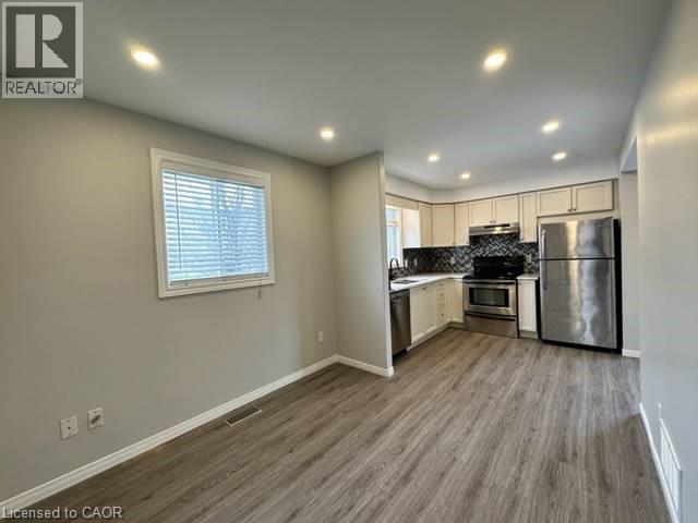 Kitchen with appliances with stainless steel finishes, healthy amount of natural light, recessed lighting, light countertops, and dark wood-style floors - 750 Paris Boulevard Unit# 1, Waterloo, ON - Indoor Photo Showing Kitchen