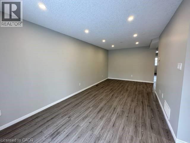 Empty room with a textured ceiling, recessed lighting, and dark wood-style flooring - 750 Paris Boulevard Unit# 1, Waterloo, ON - Indoor