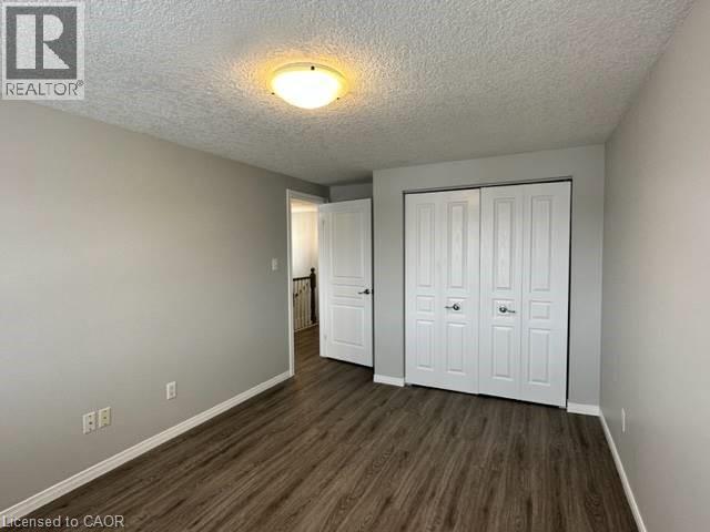 Unfurnished bedroom featuring a textured ceiling, a closet, and dark wood finished floors - 750 Paris Boulevard Unit# 1, Waterloo, ON - Indoor Photo Showing Other Room