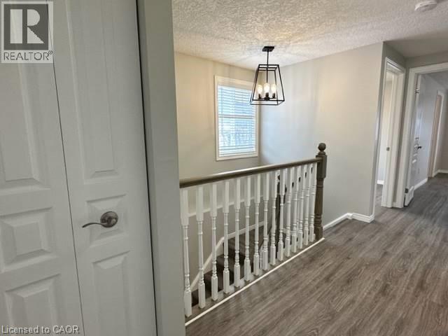 Hall with a textured ceiling, dark wood-type flooring, an upstairs landing, and a chandelier - 750 Paris Boulevard Unit# 1, Waterloo, ON - Indoor Photo Showing Other Room