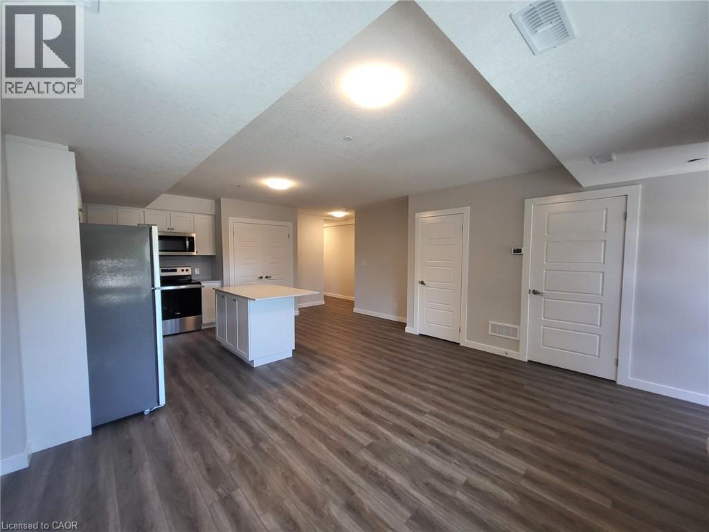 Kitchen featuring appliances with stainless steel finishes, light countertops, white cabinetry, a center island, and dark wood-style flooring - 118 Gravel Ridge Trail Unit# D16, Kitchener, ON - Indoor Photo Showing Kitchen