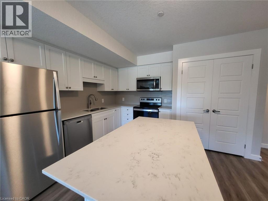 Kitchen featuring stainless steel appliances, white cabinetry, a textured ceiling, dark wood finished floors, and a kitchen island - 118 Gravel Ridge Trail Unit# D16, Kitchener, ON - Indoor Photo Showing Kitchen With Stainless Steel Kitchen With Double Sink