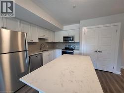 Kitchen featuring stainless steel appliances, white cabinetry, a textured ceiling, dark wood finished floors, and a kitchen island -