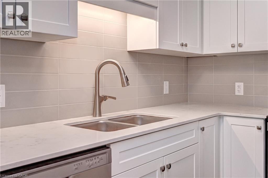Kitchen with white cabinetry, dishwasher, decorative backsplash, and light stone counters - 118 Gravel Ridge Trail Unit# C17, Kitchener, ON - Indoor Photo Showing Kitchen With Double Sink
