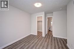 Unfurnished bedroom with a textured ceiling, a walk in closet, and wood finished floors -