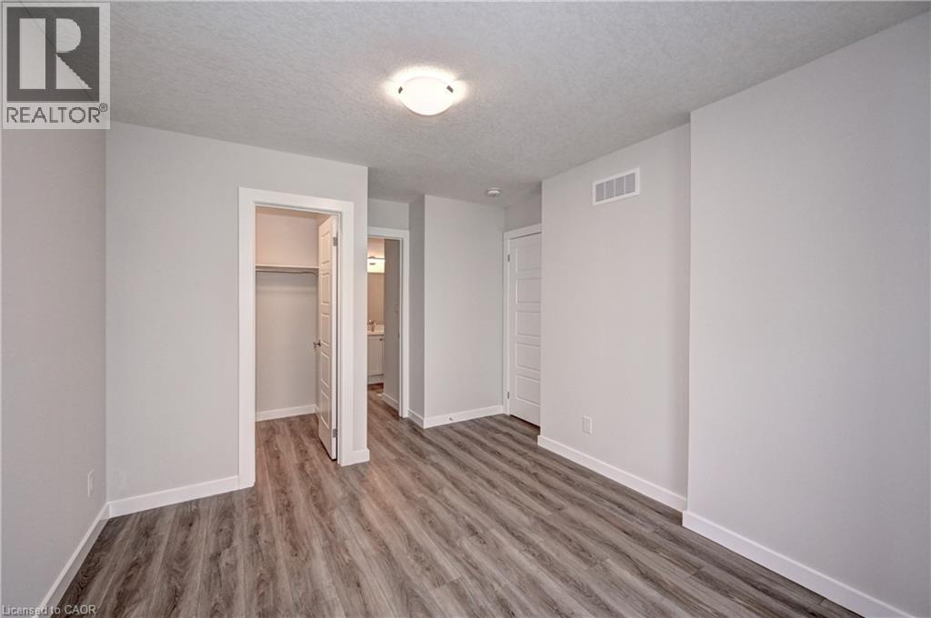 Unfurnished bedroom with a walk in closet, a textured ceiling, and light wood finished floors - 118 Gravel Ridge Trail Unit# C17, Kitchener, ON - Indoor Photo Showing Other Room