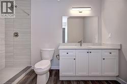 Full bathroom featuring a shower stall, vanity, and dark wood-type flooring -