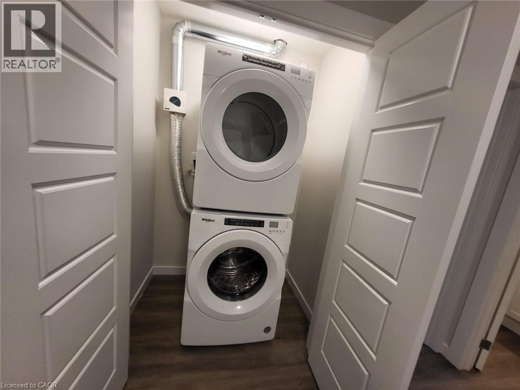 Washroom featuring stacked washer / dryer and dark wood-style flooring - 118 Gravel Ridge Trail Unit# B23, Kitchener, ON - Indoor Photo Showing Laundry Room