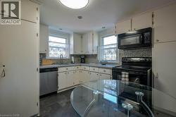 Kitchen featuring black appliances, light countertops, decorative backsplash, and healthy amount of natural light -