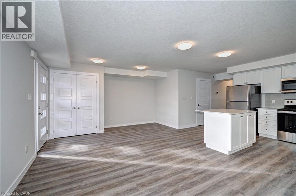 Kitchen with appliances with stainless steel finishes, white cabinetry, a kitchen island, light countertops, and a textured ceiling - 118 Gravel Ridge Trail Unit# G21, Kitchener, ON - Indoor Photo Showing Kitchen