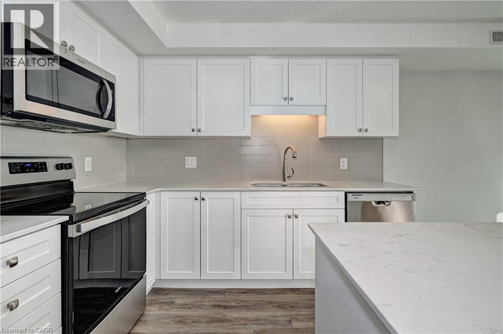 Kitchen featuring appliances with stainless steel finishes, white cabinetry, light wood-style floors, and tasteful backsplash - 118 Gravel Ridge Trail Unit# G21, Kitchener, ON - Indoor Photo Showing Kitchen With Stainless Steel Kitchen With Double Sink With Upgraded Kitchen