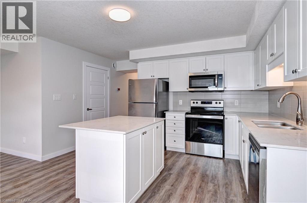 Kitchen with appliances with stainless steel finishes, white cabinetry, light stone counters, tasteful backsplash, and a textured ceiling - 118 Gravel Ridge Trail Unit# G21, Kitchener, ON - Indoor Photo Showing Kitchen With Stainless Steel Kitchen With Double Sink