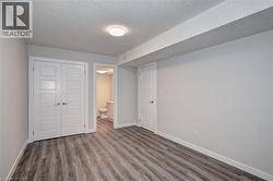Unfurnished bedroom with wood finished floors, a textured ceiling, a closet, and connected bathroom -