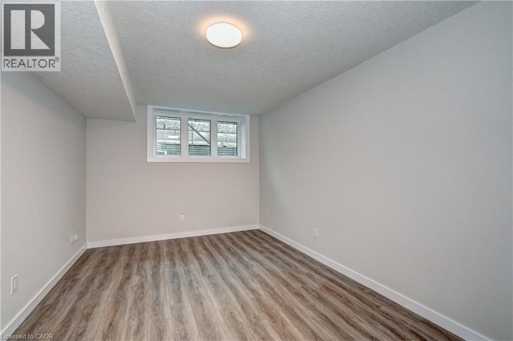Empty room with a textured ceiling and light wood-type flooring - 118 Gravel Ridge Trail Unit# G21, Kitchener, ON - Indoor Photo Showing Other Room