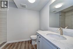 Full bathroom with tiled shower, vanity, light wood finished floors, and a textured ceiling -