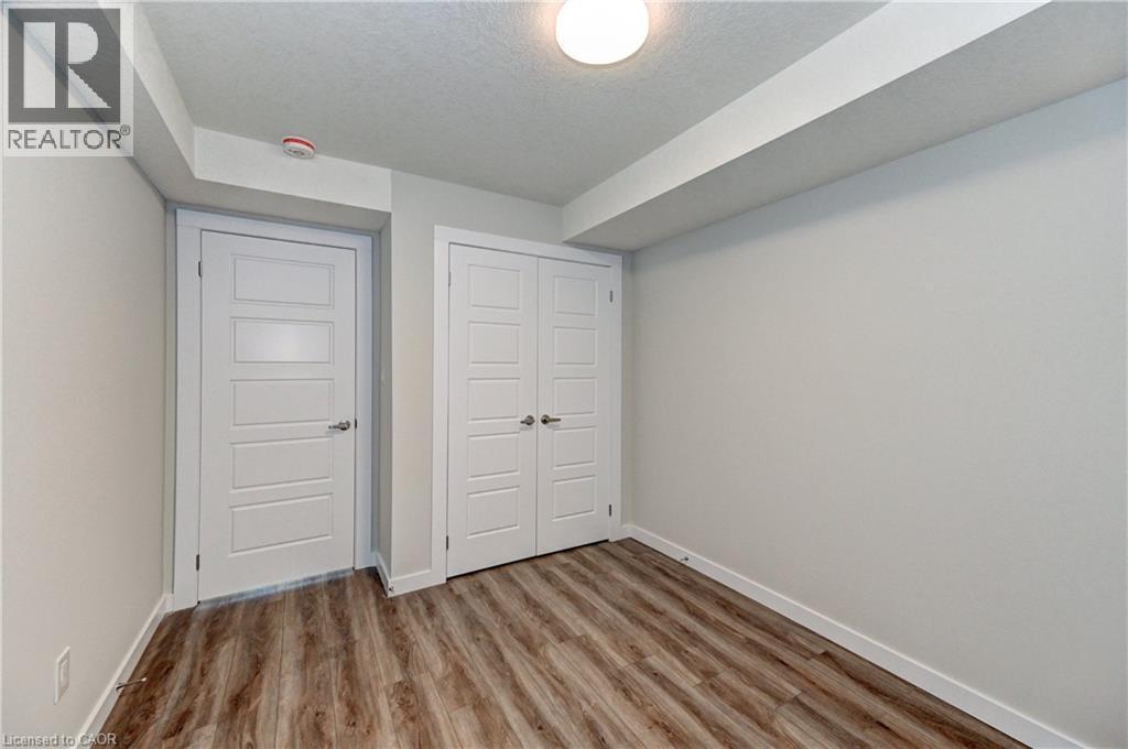 Unfurnished bedroom featuring wood finished floors, a textured ceiling, and a closet - 118 Gravel Ridge Trail Unit# G21, Kitchener, ON - Indoor Photo Showing Other Room