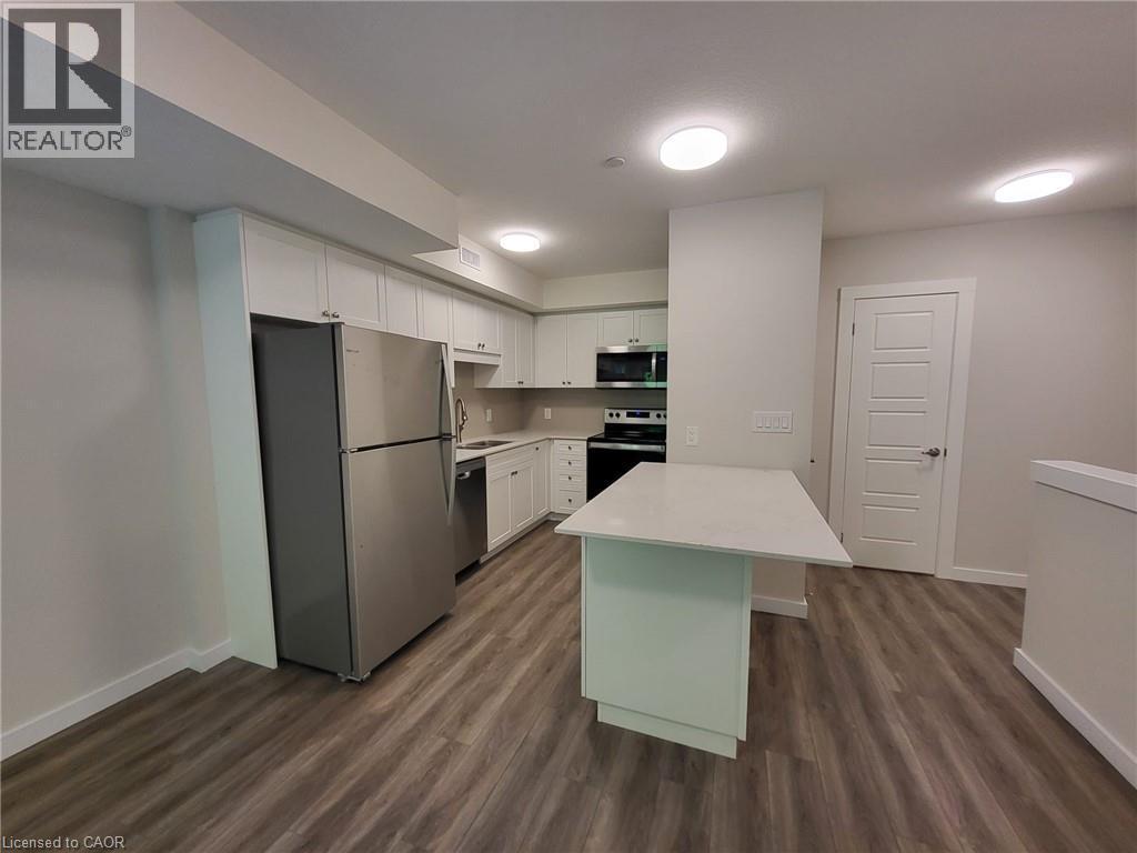 Kitchen featuring appliances with stainless steel finishes, white cabinetry, dark wood-style floors, and a peninsula - 118 Gravel Ridge Trail Unit# F17, Kitchener, ON - Indoor Photo Showing Kitchen With Stainless Steel Kitchen
