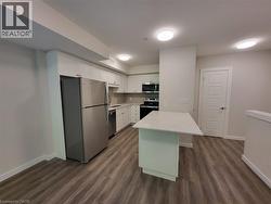 Kitchen featuring appliances with stainless steel finishes, white cabinetry, dark wood-style floors, and a peninsula -