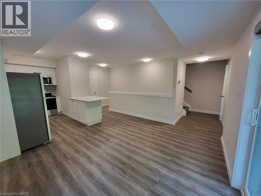 Kitchen featuring a peninsula, stainless steel appliances, light countertops, dark wood-type flooring, and white cabinetry - 118 Gravel Ridge Trail Unit# F17, Kitchener, ON - Indoor Photo Showing Other Room