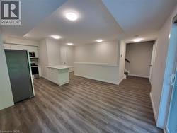 Kitchen featuring a peninsula, stainless steel appliances, light countertops, dark wood-type flooring, and white cabinetry -