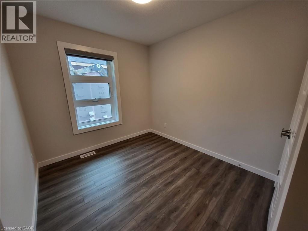 Empty room with dark wood-type flooring and baseboards - 118 Gravel Ridge Trail Unit# F17, Kitchener, ON - Indoor Photo Showing Other Room