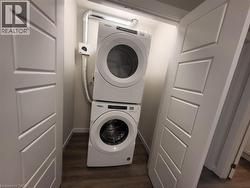 Washroom featuring stacked washer / dryer and dark wood-style flooring -
