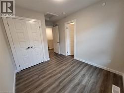 Unfurnished bedroom with attic access, dark wood-style floors, and a closet -