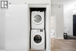 Laundry room with stacked washer and clothes dryer and baseboards -