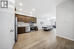 Kitchen with stainless steel appliances, dark brown cabinetry, pendant lighting, recessed lighting, and light wood finished floors -