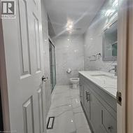 Bathroom featuring vanity, toilet, an enclosed shower, and tile walls -